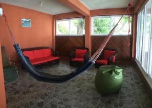 a room with a hammock and two chairs and windows at La Cabaña de Andre in Nimá