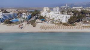 an aerial view of a beach with chairs and buildings at Aparthotel Ses Fotges in Playa de Muro