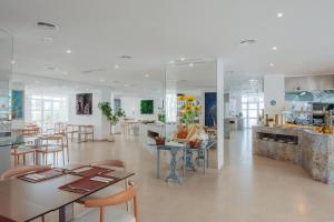 a restaurant with tables and chairs and a kitchen at Aparthotel Ses Fotges in Playa de Muro