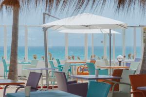 a beach with tables and chairs and people on the beach at Aparthotel Ses Fotges in Playa de Muro