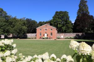 uma antiga casa de tijolos com um grande quintal com flores brancas em The Walled Garden at Woodhall Estate em Hertford