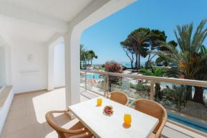 a table and chairs on a balcony with a view of the ocean at Aparthotel Ses Fotges in Playa de Muro