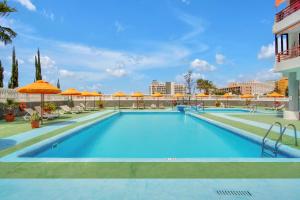 ein Pool in einem Hotel mit orangefarbenen Sonnenschirmen in der Unterkunft ON THE BEACH, Sea View, Fast Fiber, Pool, Parking in Playa de las Americas