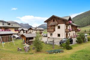 a village in the mountains with a house and cars at Terra Chalet Martina in Livigno