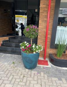 a large blue pot with flowers in front of a building at AVENIDA HOTEL DE RESENDE in Resende