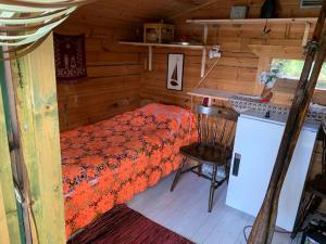 1 dormitorio en una cabaña de madera con 1 cama y 1 silla en Kesämökki Kalliola Heinola, en Ahvenisto