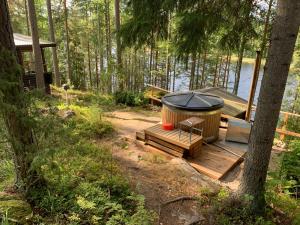 una bañera en una terraza de madera junto a un lago en Kesämökki Kalliola Heinola, en Ahvenisto