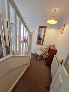 a hallway with a stairway with a chair and a mirror at Endeavour Cottage - A Wonderful Whitby Holiday in Whitby