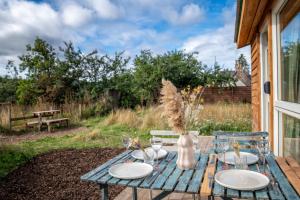 a picnic table with plates and glasses on it at Charming boutique forest view cabin with hot tub in Ballater in Ballater