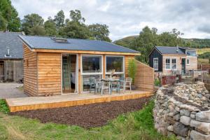 une petite maison avec une terrasse et une table dans l'établissement Charming boutique forest view cabin with hot tub in Ballater, à Ballater