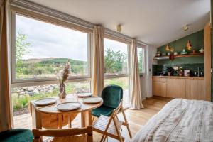 a dining room with a table and a large window at Alba - Charming boutique forest view cabin with hot tub in Ballater in Ballater