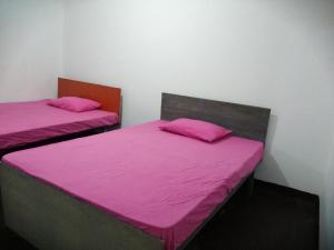 duas camas num quarto com lençóis cor-de-rosa em Udara's Colombo Rooms em Battaramulla