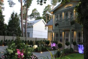 a house with a fence and a yard with flowers at Villa Lettonia in Jūrmala