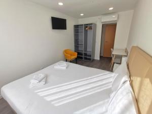 a bedroom with a white bed and a chair at Vila Alexandra in Costa da Caparica