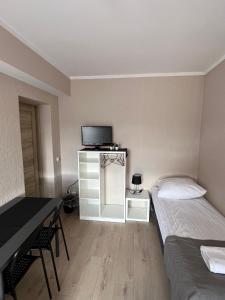 a room with two beds and a desk and a television at Kwatery prywatne Jaśmin in Gniezno