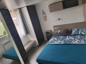 a bedroom with a bed with a blue comforter at Mobil-home L'Olivier in Fréjus
