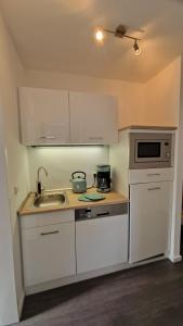 a kitchen with white cabinets and a sink and a microwave at Ilse 59 in Bad Harzburg