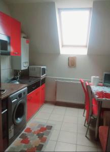 a kitchen with red cabinets and a table and a window at Apartament Sarah in Oţelu Roşu