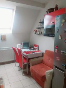 a kitchen with a table with red chairs and a refrigerator at Apartament Sarah in Oţelu Roşu