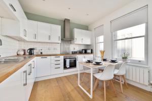 a kitchen with white cabinets and a table and chairs at The i360 flat, penthouse, sea view, large private roof terrace, central Brighton 2 bedroom, up to 6 guests in Brighton & Hove