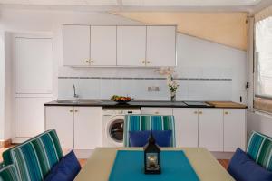 a kitchen with white cabinets and a table and chairs at Casa Luis Montesdeoca in Puerto de Mogán