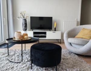 uma sala de estar com uma televisão, uma cadeira e um banco em Villa Creole 0308 Luxe appartement met verwarmd zwembad Nieuwpoort Jachthaven em Nieuwpoort