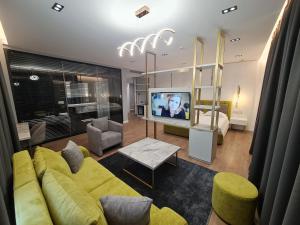 a living room with a yellow couch and a tv at Regina City Hotel & SPA in Vlorë