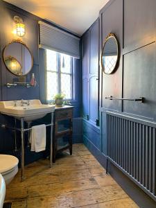 een badkamer met blauwe muren en een wastafel en spiegel bij Smugglers Cottage in Hastings