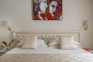 a bedroom with a white bed with a painting on the wall at Hotel Re Enzo in Bologna