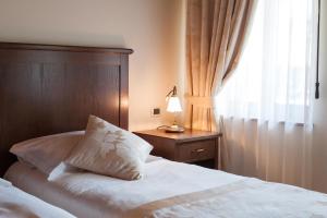 a bedroom with a bed with a lamp and a window at Hotel & Restaurant Pahor in Doberdò del Lago