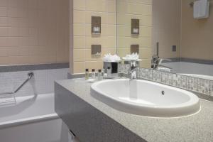 a bathroom with two sinks and a bathtub at Oulton Hall Hotel, Spa & Golf Resort in Leeds