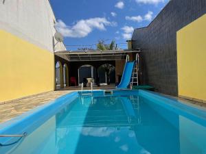 une piscine avec toboggan en face d'un bâtiment dans l'établissement Casa com piscina Balneario Ipanema PR, à Pontal do Paraná