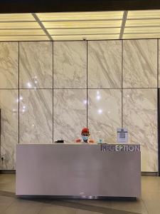a person sitting at a reception desk in a building at Infini Suites@ Continew Residence KL in Kuala Lumpur