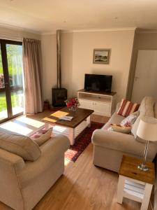 a living room with two couches and a television at Peartree Cottage in Hogsback