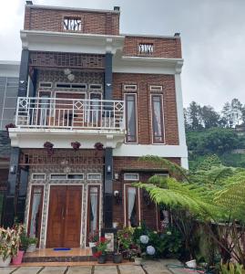 um edifício de tijolos com uma varanda em cima em Sapo Rumbia Villa & Hotel em Berastagi