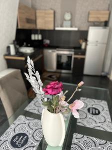 eine weiße Vase mit rosa Blumen auf einem Glastisch in der Unterkunft Schöne 3 Zimmer Wohnung in Oberwesel