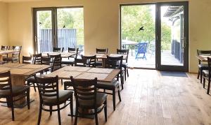 a restaurant with wooden tables and chairs and a patio at Hotel garni Hof Wetzenow in Rossow +23 photos