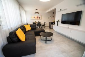 - un salon avec un canapé noir et des oreillers jaunes dans l'établissement Azzurro apartment - with rooftop jacuzzi, à Zadar