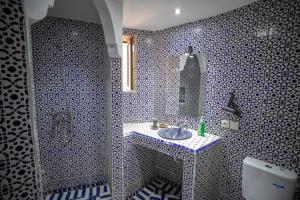 a blue and white bathroom with a sink and a mirror at Dar Hafsa in Fez