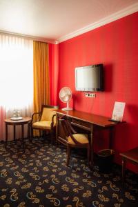 a hotel room with a desk and a television on a red wall at Landhaus Hotel Neuss in Neuss