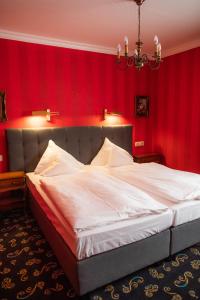 a bedroom with a large white bed with red walls at Landhaus Hotel Neuss in Neuss