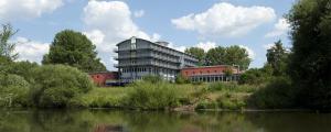 a large building next to a river with trees at Jugendherberge Hannover in Hannover