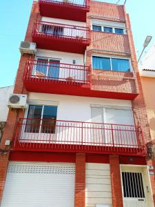 un edificio de apartamentos con balcones rojos y puertas blancas en SDH apartments, en Alicante