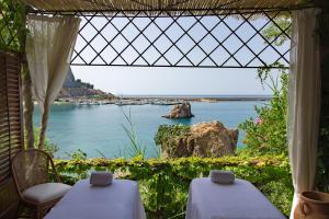 een kamer met 2 tafels en uitzicht op het water bij Le Calette N.5 in Cefalù