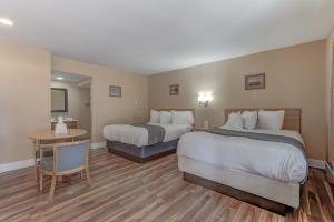 a hotel room with two beds and a table at Shasta Pines Motel & Suites in Burney