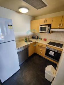 a small kitchen with a refrigerator and a sink at ZEN88 ESPLANADE: 1-BR Top Floor Ocean View Suite in Darwin