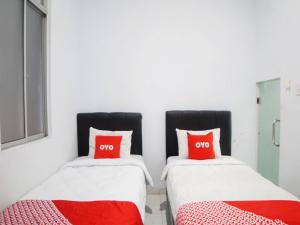 2 letti in una camera con cuscini rossi di SUPER OYO 91627 Wika Wiki Homestay a Medan