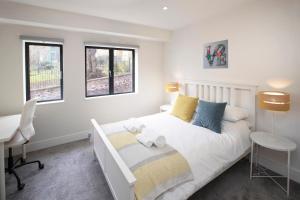 a bedroom with a bed and a desk and windows at Large family, city centre Coach House in Bristol