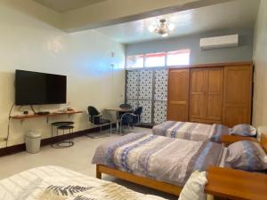 Changhua County的住宿－彰濱伸港民宿，一间卧室配有两张床、一张桌子和一台电视。
