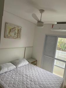 a white bed in a bedroom with a ceiling fan at Ubatuba in Ubatuba